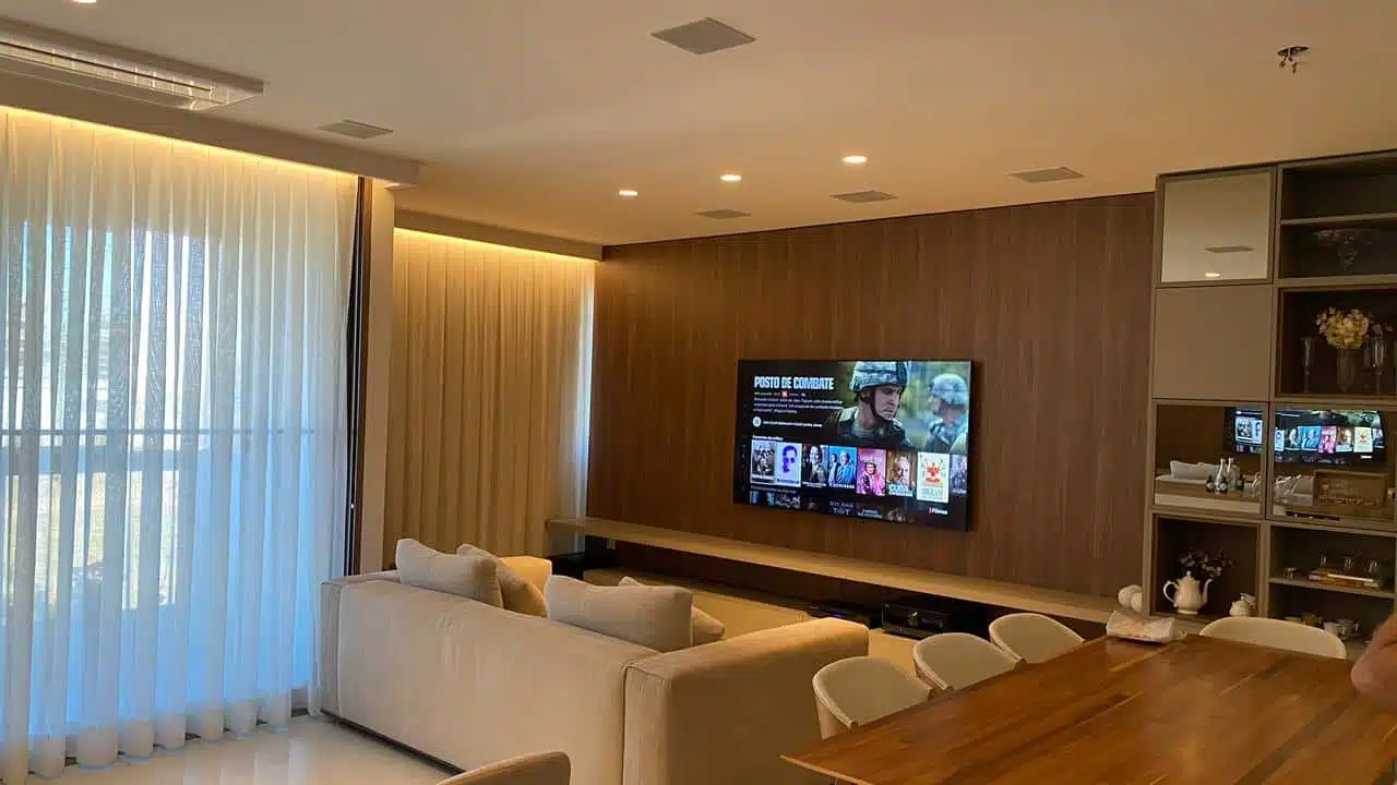 Sala de estar com home theater embutido no painel de madeira
